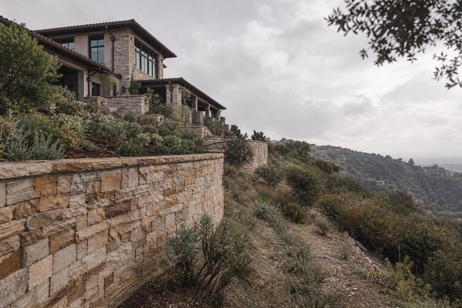 Hillside homes above a stone retaining wall in Woodland Hills