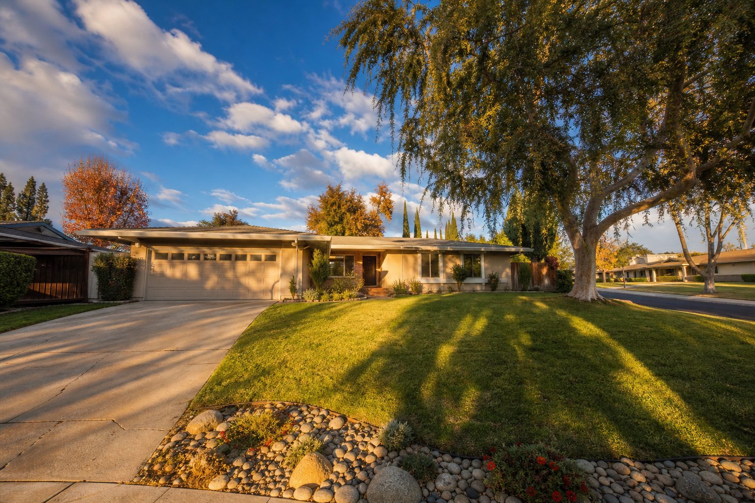 Single-story ranch home with mature pepper tree and wide driveway in a Northridge residential neighborhood at golden hour.