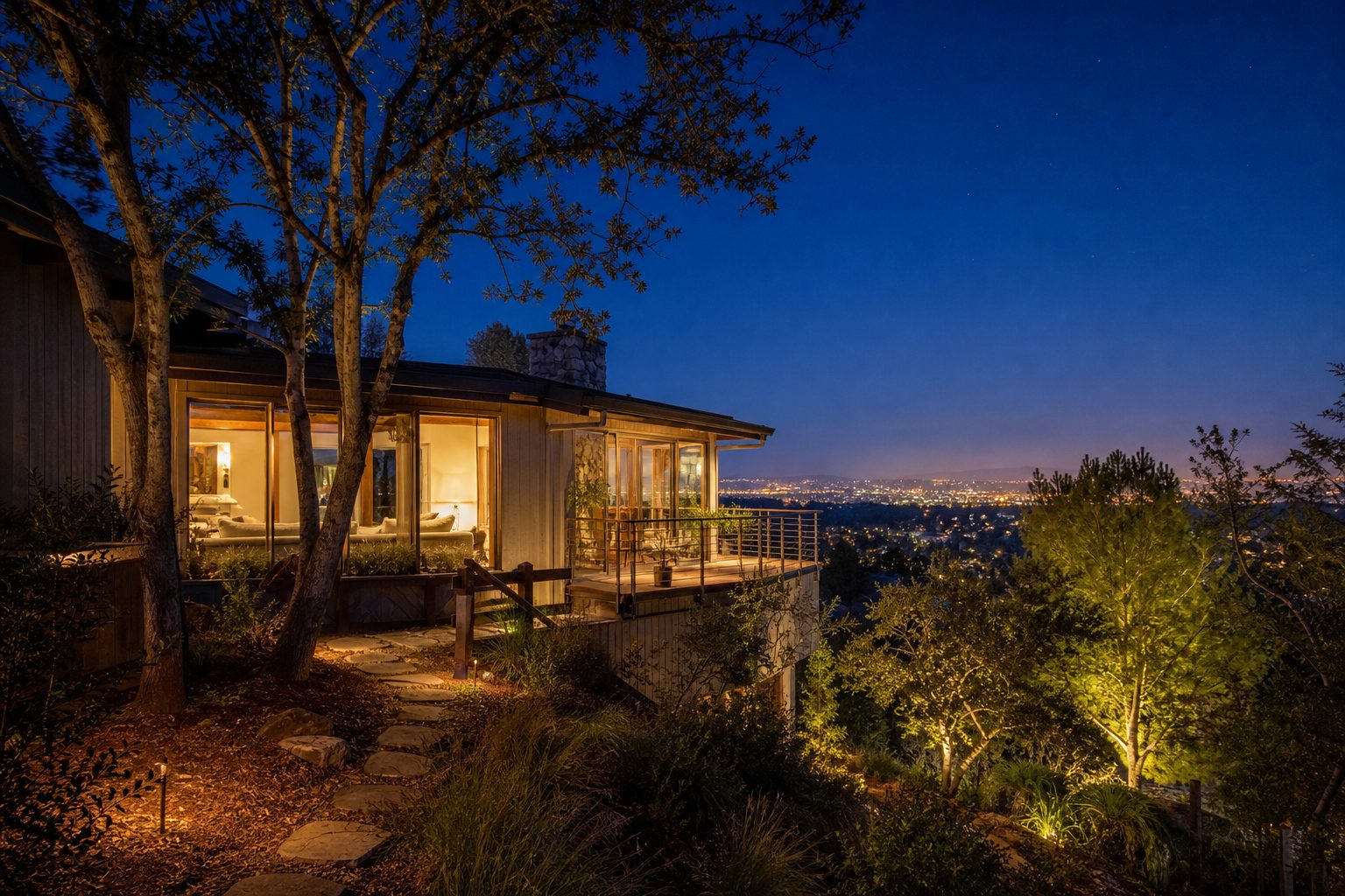 Woodland Hills hillside home glowing warmly at dusk with manicured defensible space and cleared vegetation surrounding the property.