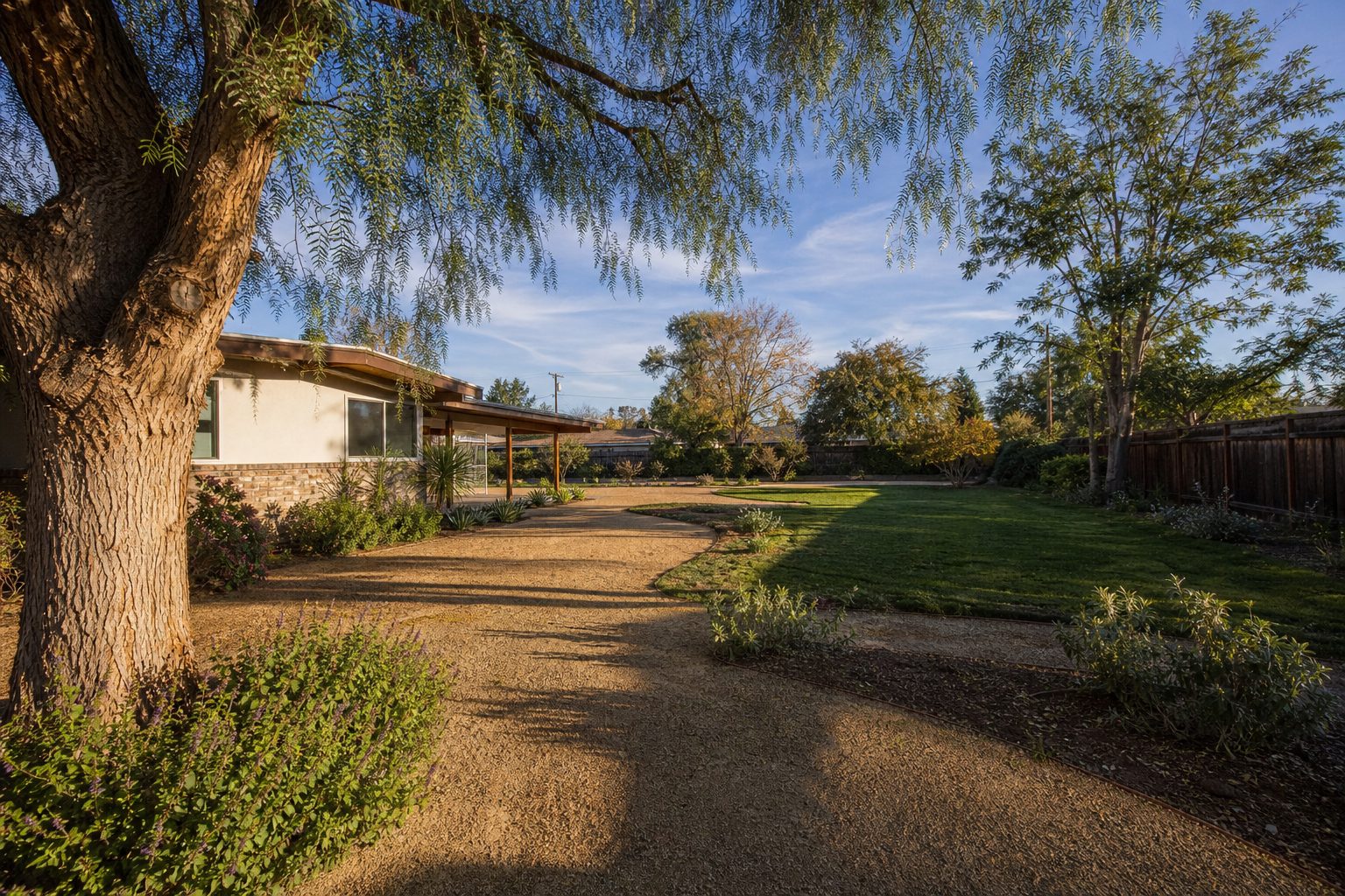 Large Lake Balboa ranch home with spacious, flat backyard and mature pepper tree showing ample ADU development potential.