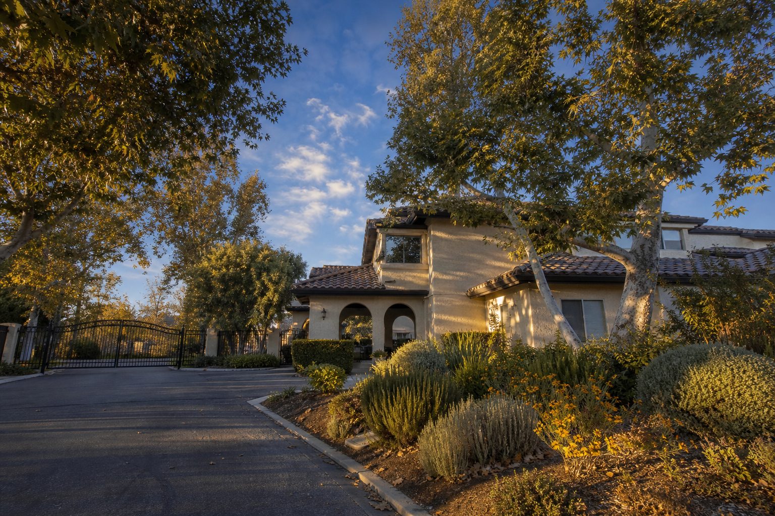Gated community clubhouse in Woodland Hills with mature trees and Mediterranean-style architecture at sunset.