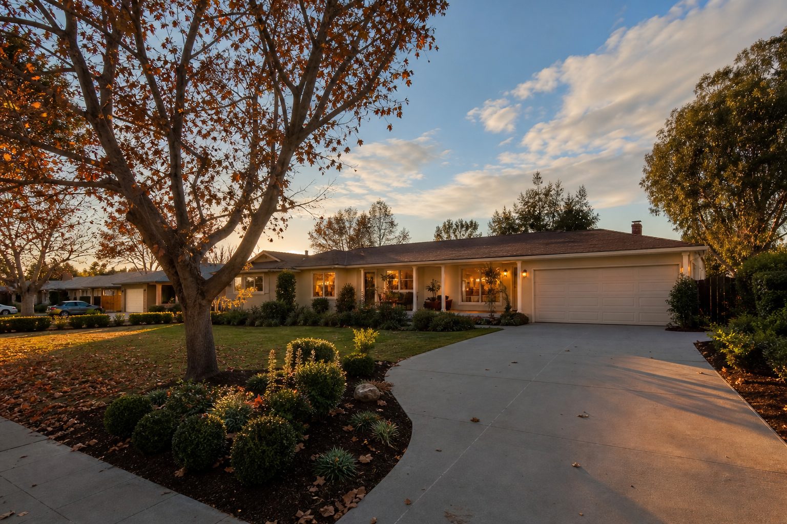 Single-story 1960s ranch home with wide porch and mature trees on tree-lined Northridge street in golden hour light.