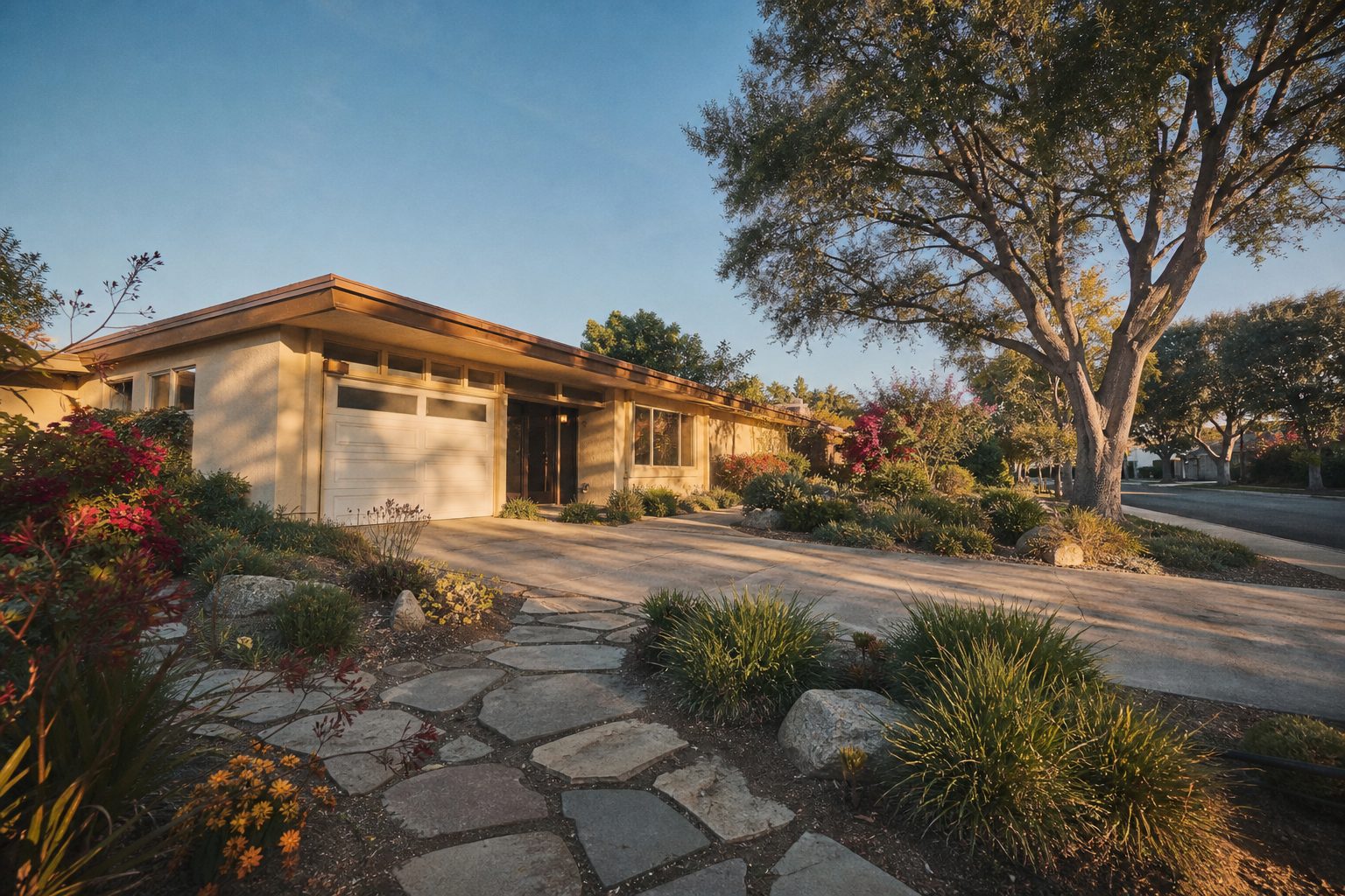 Single-story stucco home with mature pepper trees and stone walkway in Northridge at golden hour.