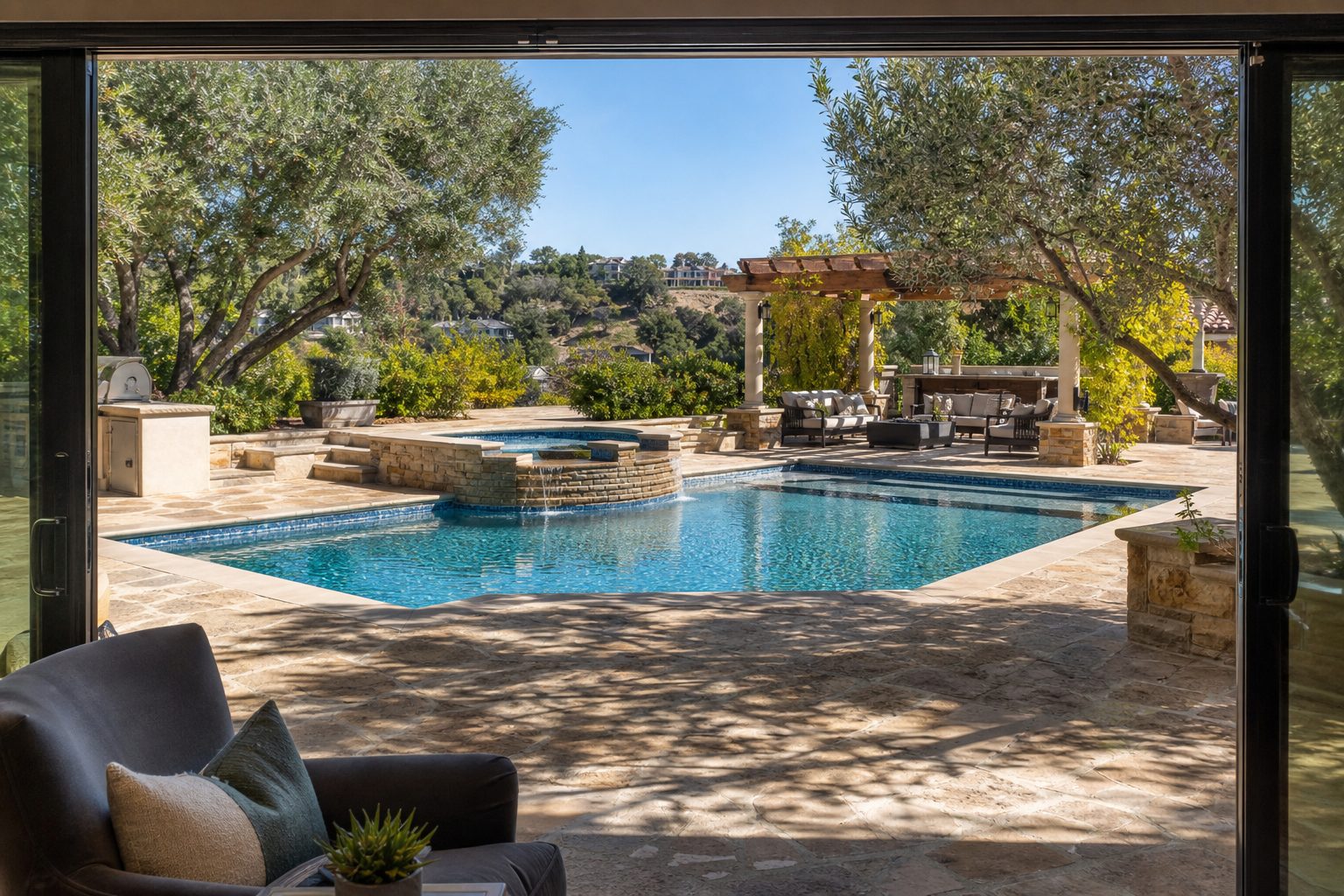 Resort-style backyard with pool, spa, travertine deck, and mature trees in Woodland Hills neighborhood.