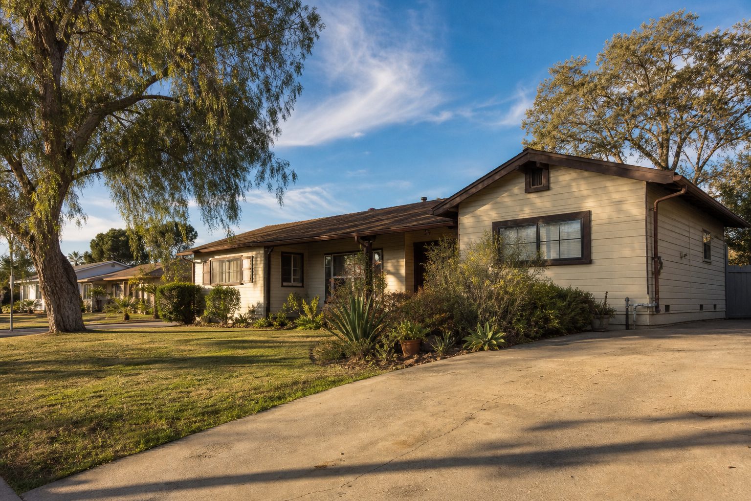 Cream-colored 1950s ranch home with mature pepper tree and weathered plumbing in Lake Balboa residential neighborhood.