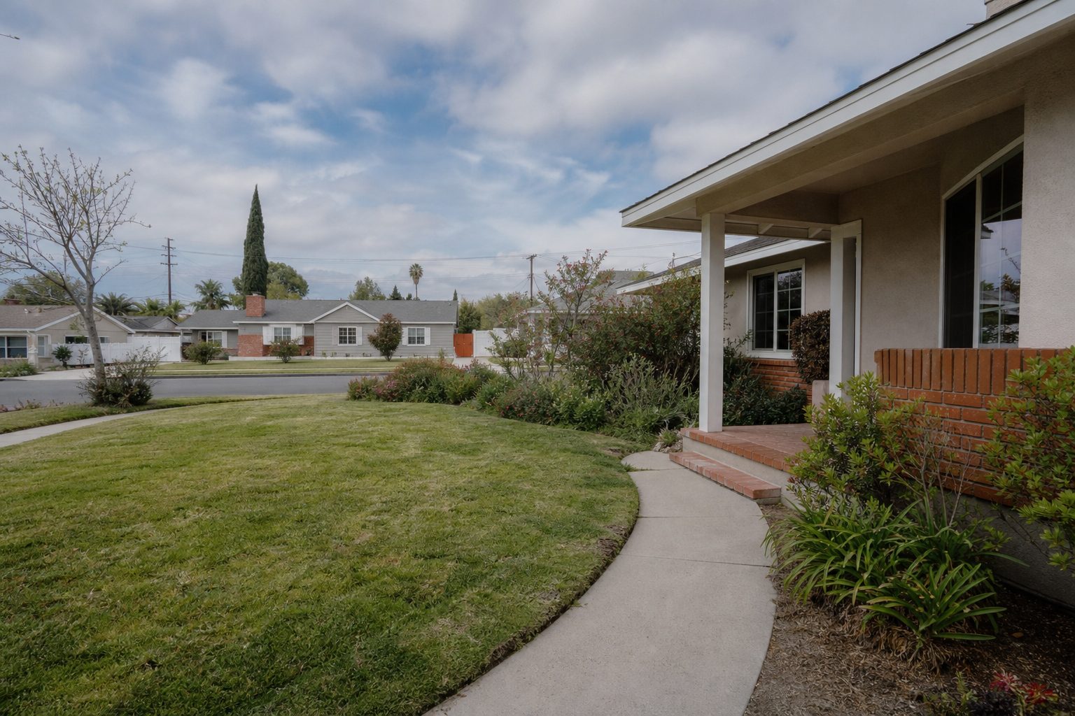 Three-bedroom North Hills ranch home with front lawn, concrete walkway, and natural Valley landscaping.
