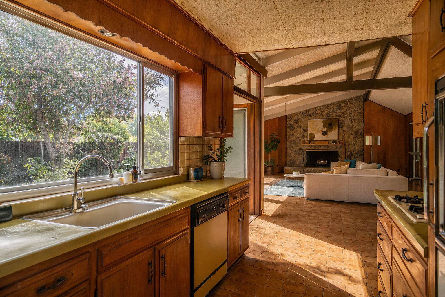 Light-filled kitchen with period wood cabinetry and mature backyard trees, typical Northridge 1970s home interior.